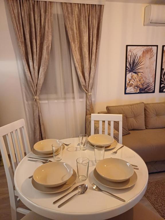 una mesa blanca con platos y cubiertos en Apartman Silver Lux Srebrno jezero, en Veliko Gradiste
