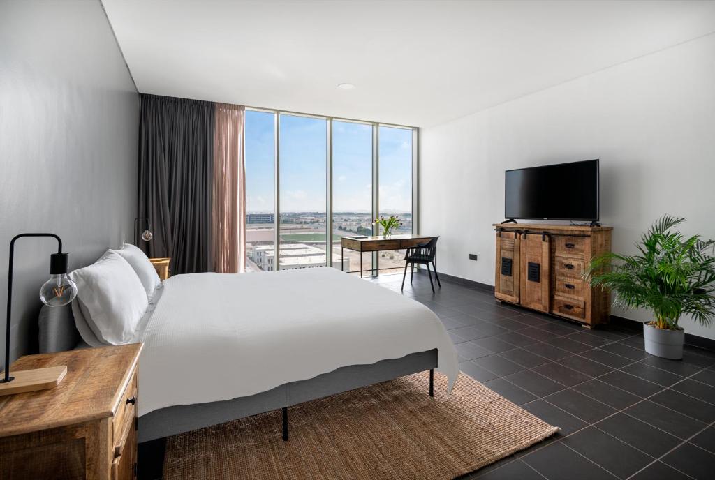 una camera d'albergo con un grande letto e una TV di Emirates Sports Hotel Apartments, Dubai Sports City a Dubai