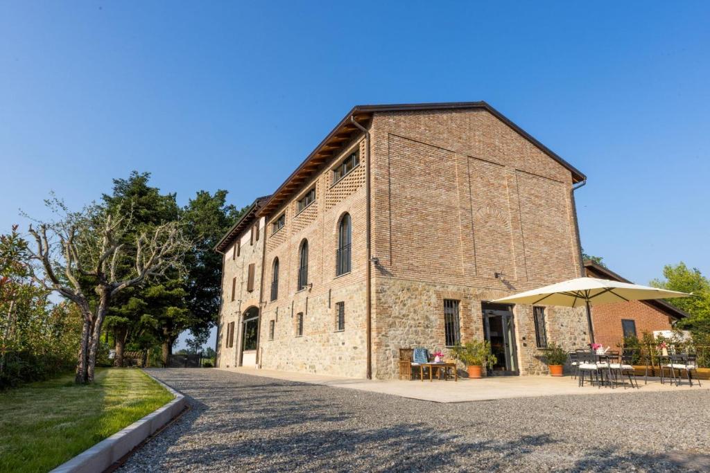 ein altes Backsteingebäude mit Tischen und einem Regenschirm in der Unterkunft Agriturismo I Tre Colli in Viazzano