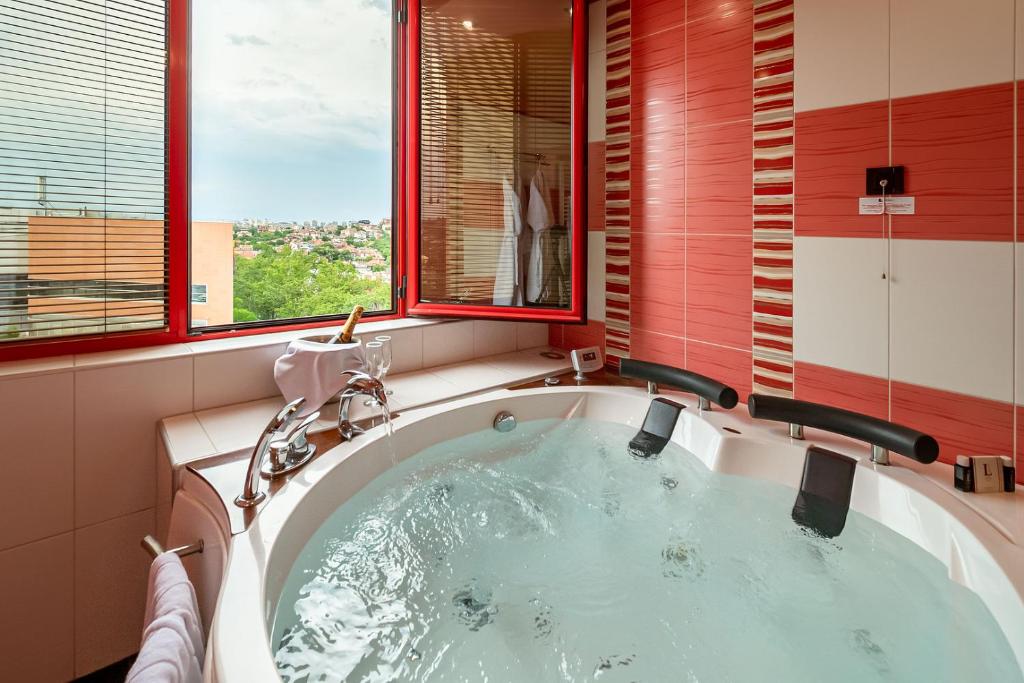 una bañera en un baño con ventana en Hotel Leipzig, en Plovdiv