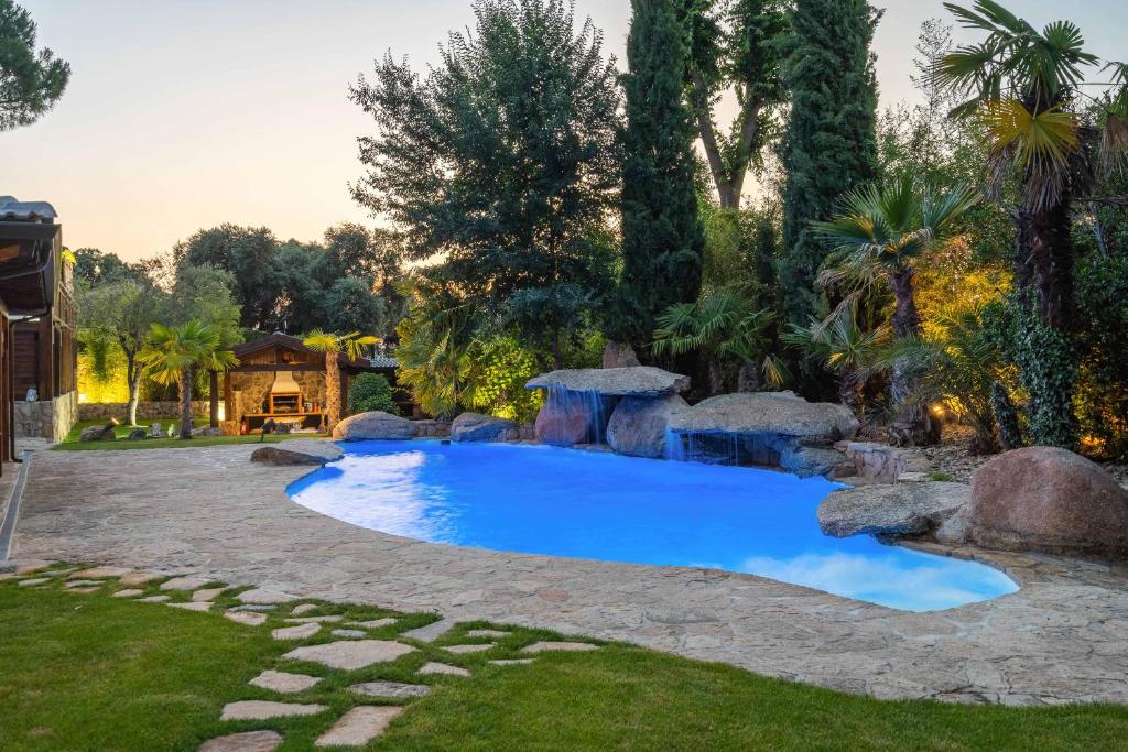 een zwembad in een achtertuin met rotsen en bomen bij For You Rentals Finca Rural el Caribe en Madrid GAM4 in Batres