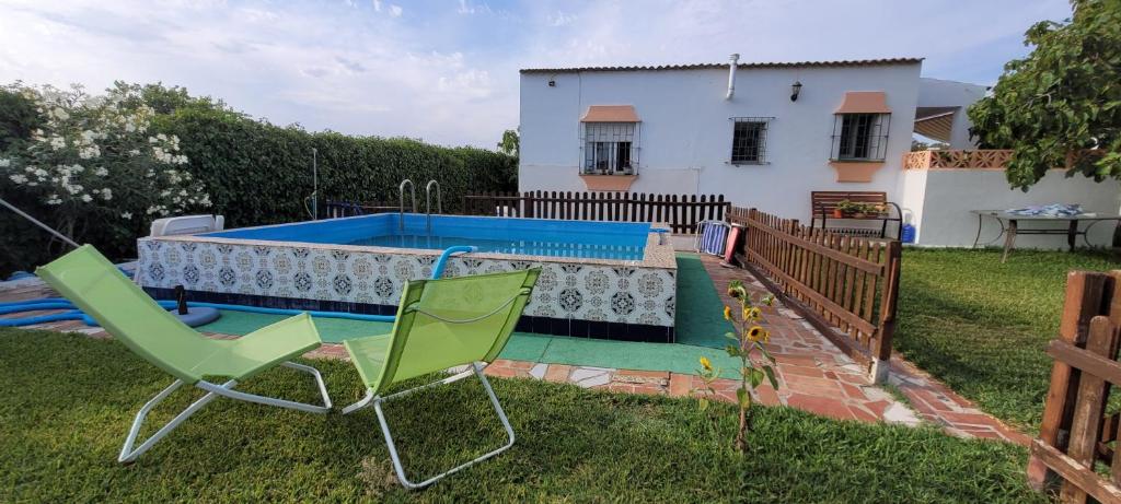 une cour avec deux chaises et une piscine dans l'établissement Casa con piscina privada y jardín, à Chiclana de la Frontera