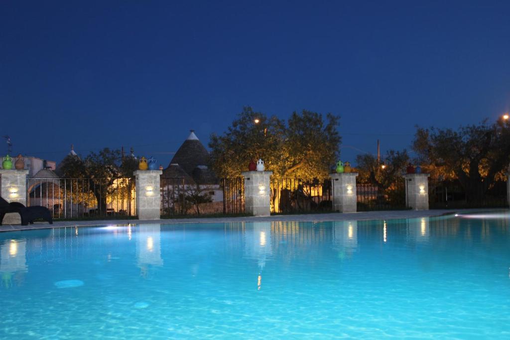 a large swimming pool in front of a building at night at Il Gabellota Resort in Alberobello