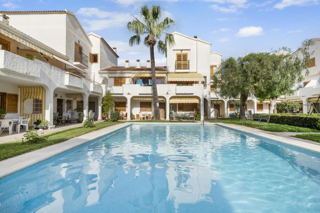 - une piscine en face d'une maison avec un palmier dans l'établissement Tu casita de la playa, à Santa Pola