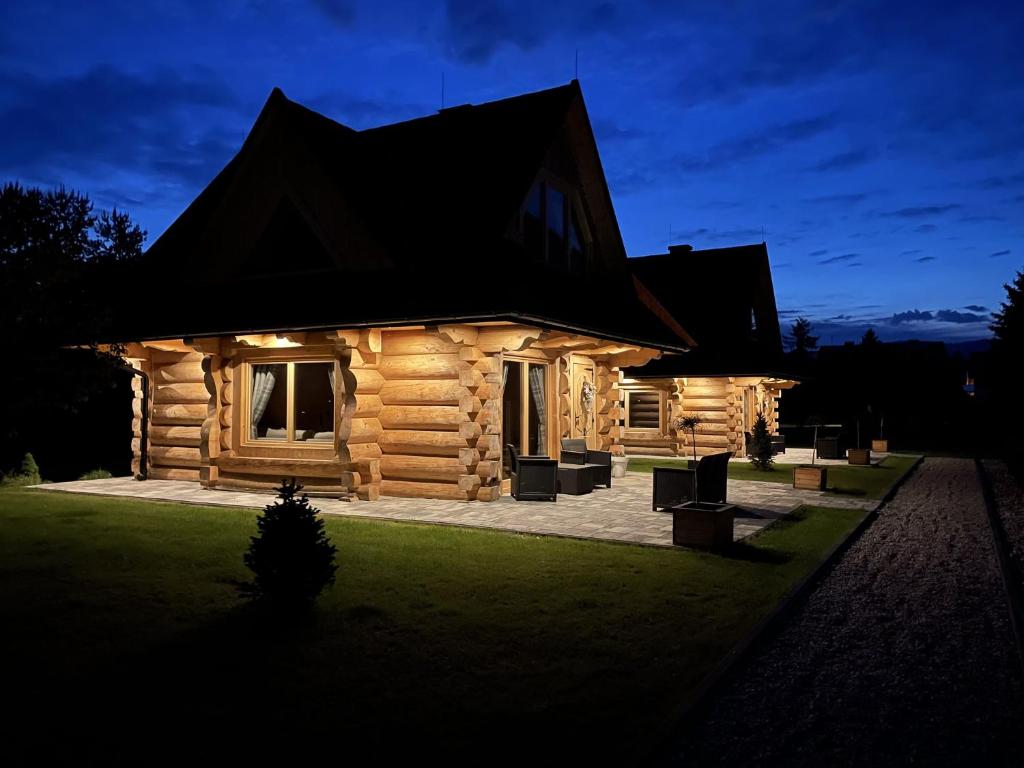 una cabaña de madera por la noche con las luces encendidas en Osada Frycówka, en Nowy Targ