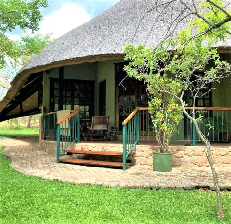 una pequeña casa verde con techo de paja en Double lodge on natural African bush - 2112 en Bulawayo