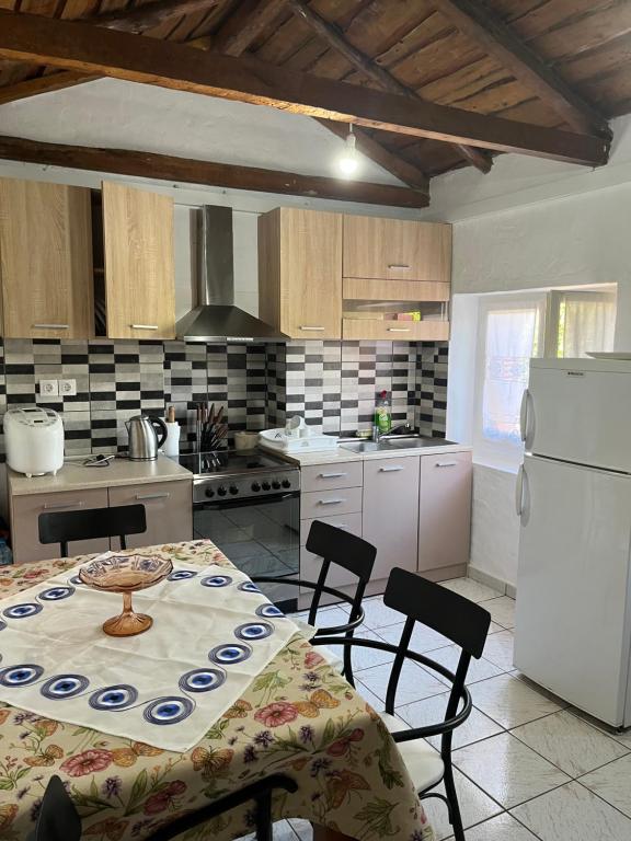 a kitchen with a table and chairs and a white refrigerator at Rodovani Cottage in Antípaxos