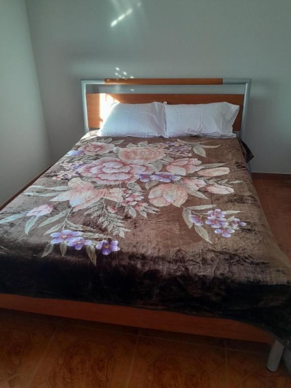 a bed with a floral comforter and pillows at Beach,surf, hiking and more in Maceira