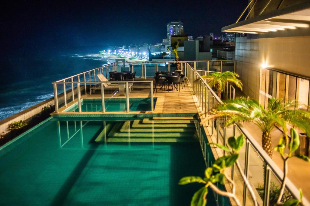 a balcony of a building with a swimming pool at night at Paradiso Macae Hotel in Macaé