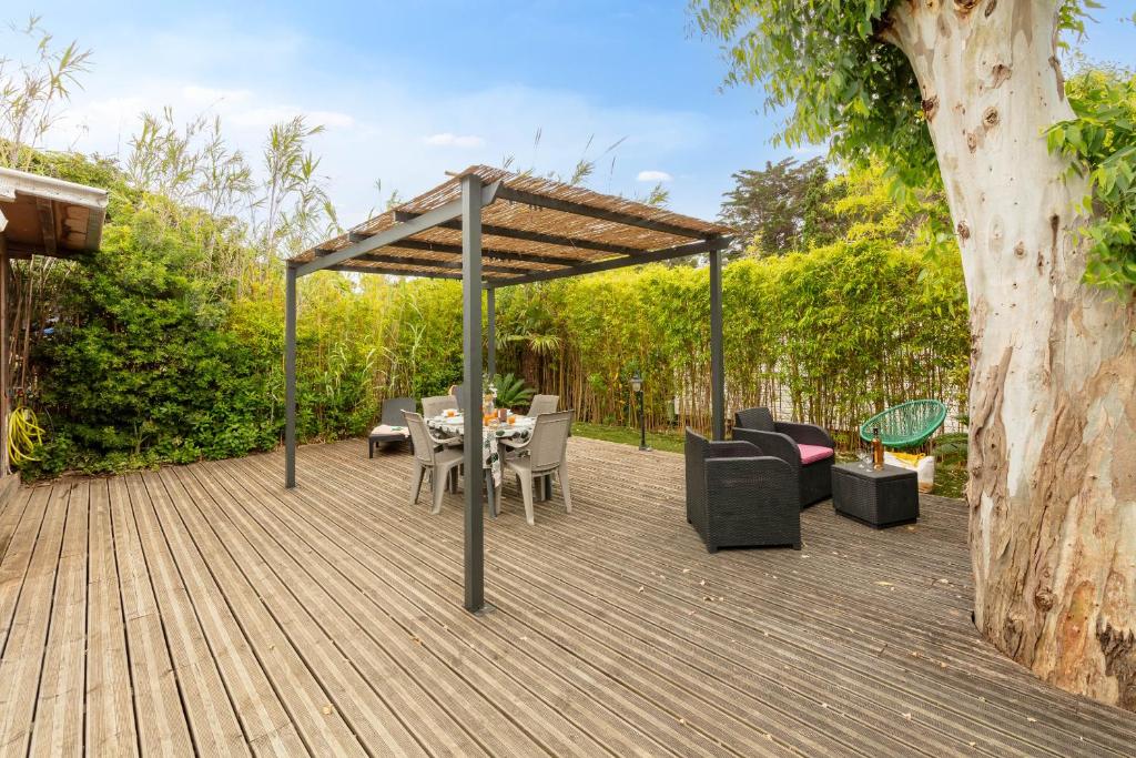 une terrasse en bois avec une pergola, une table et des chaises dans l'établissement L'Eucalyptus, mobil-home avec extérieur spacieux à quelques mètres de la mer, à Hyères