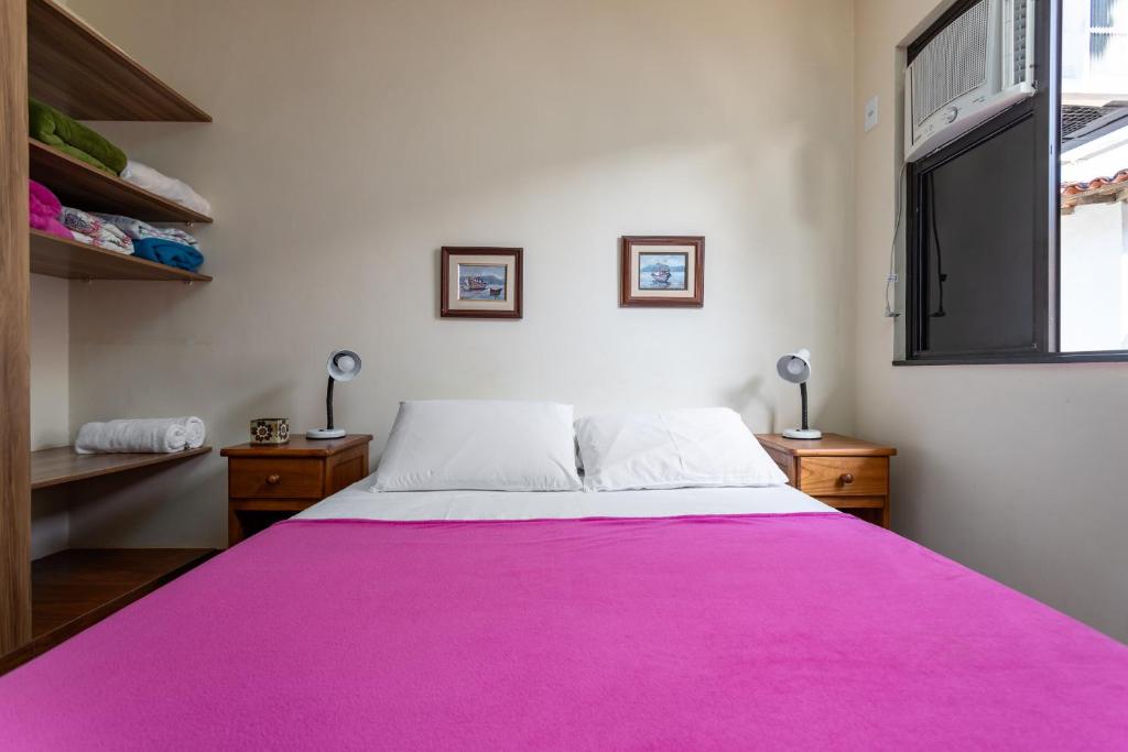 Una cama grande con una manta rosa encima. en Apart Hotel Pet Friendly em Búzios, en Búzios