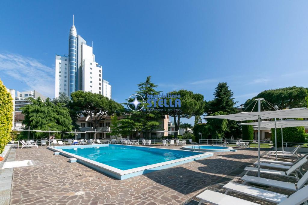 einen Pool mit Stühlen und Sonnenschirmen in einer Stadt in der Unterkunft Residence Equilio in Lido di Jesolo