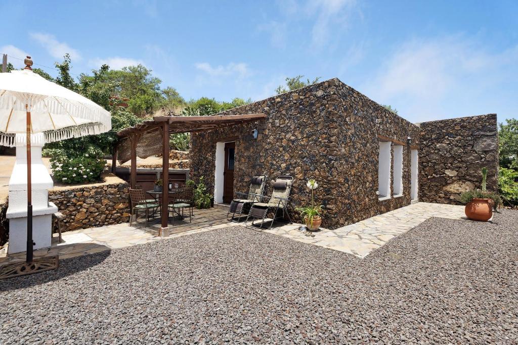 a stone house with a patio and an umbrella at La Casa de Abajo in Valverde