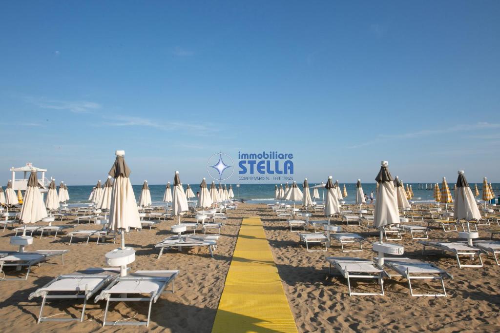a beach with chairs and umbrellas and the ocean at Villa Alpina in Lido di Jesolo