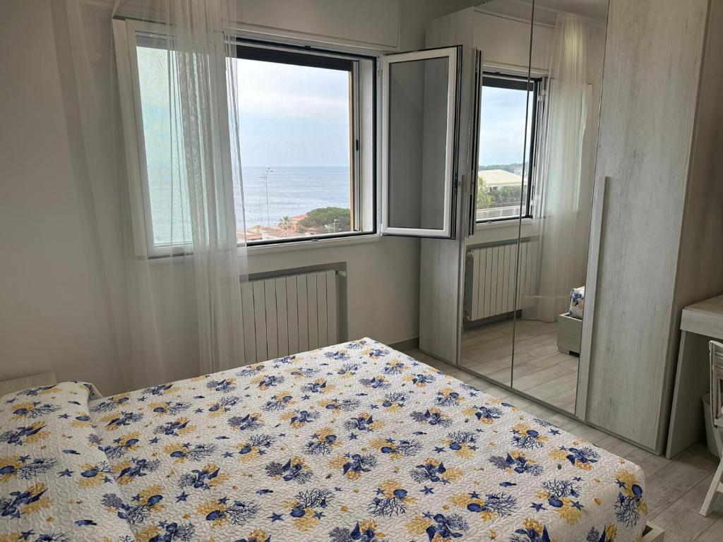 een slaapkamer met een bed en uitzicht op de oceaan bij Camere private vista Faraglioni - Aci Trezza in Aci Castello