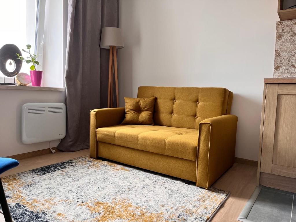żółtą kanapę w salonie z dywanem w obiekcie 3 Budget Stay Apartments w mieście Zgorzelec