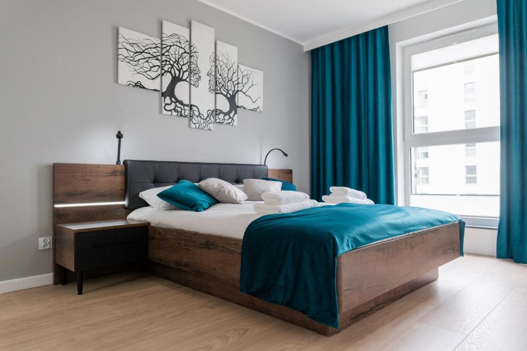 a bedroom with a bed with blue sheets and a window at Flatbook - City Center Apartments Angielska Grobla in Gdańsk