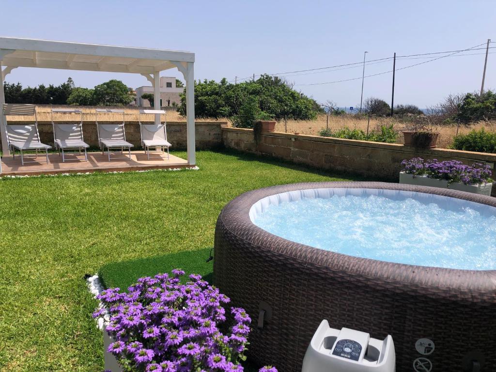 une cour avec un bain à remous et quelques fleurs violettes dans l'établissement Villa Rosa zona Torre San Giovanni, à Torre San Giovanni