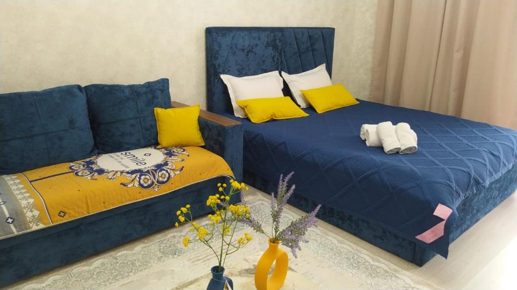 a bedroom with two beds and a blue couch at Гранд Чемпион in Astana