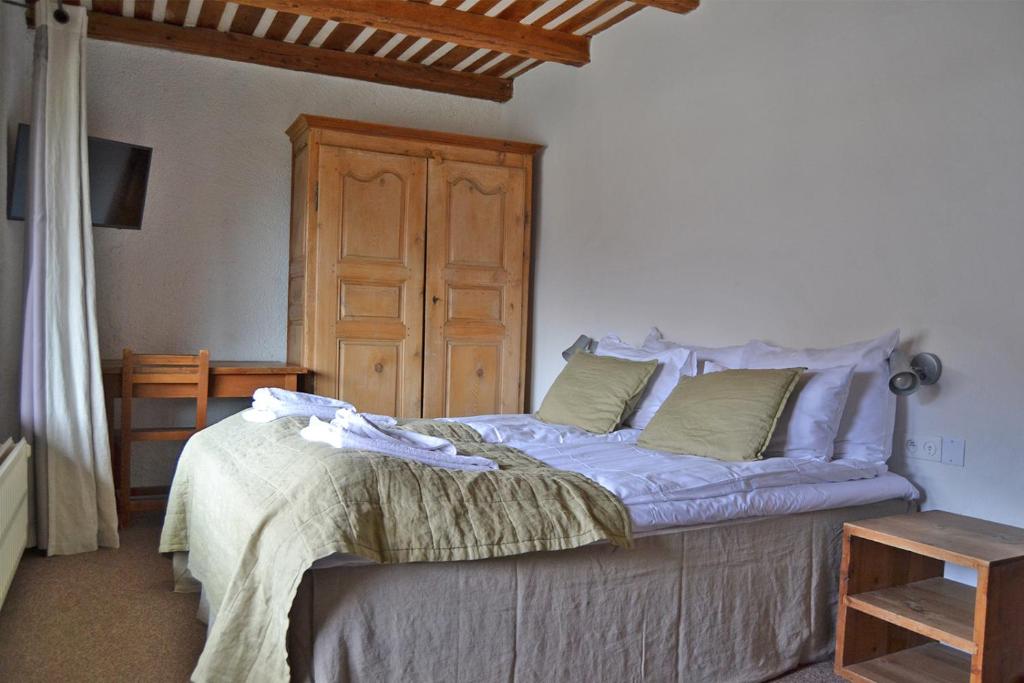 une chambre avec un lit et une armoire en bois dans l'établissement Langley Hotel La Vieille Ferme, à La Salle Les Alpes