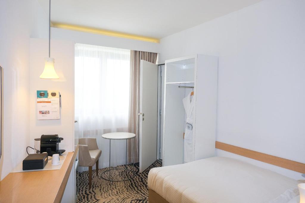 a hotel room with a bed and a desk and a table at Thalazur Ouistreham - Hôtel & Spa in Ouistreham