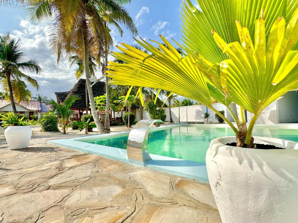 uma piscina com uma palmeira ao lado de uma casa em TIANDE Boutique Hotel em Pwani Mchangani
