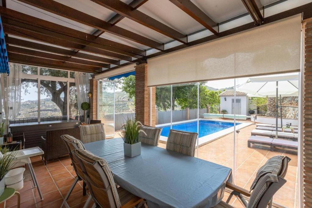 een eetkamer met een tafel en een zwembad bij Villa Flamenca, comoda con piscina privada, barbacoa carril asfaltado by CostaDelSolEscapes in Canillas de Albaida