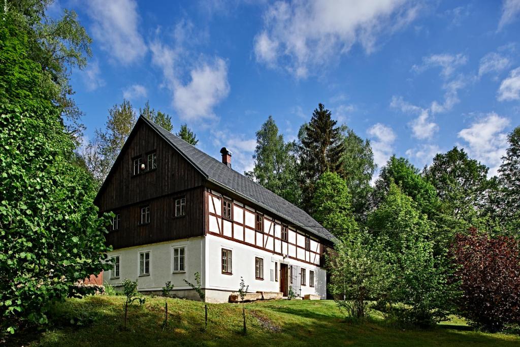 a large barn with a black roof on a field at Chalupa Poustevna in Dolní Poustevna