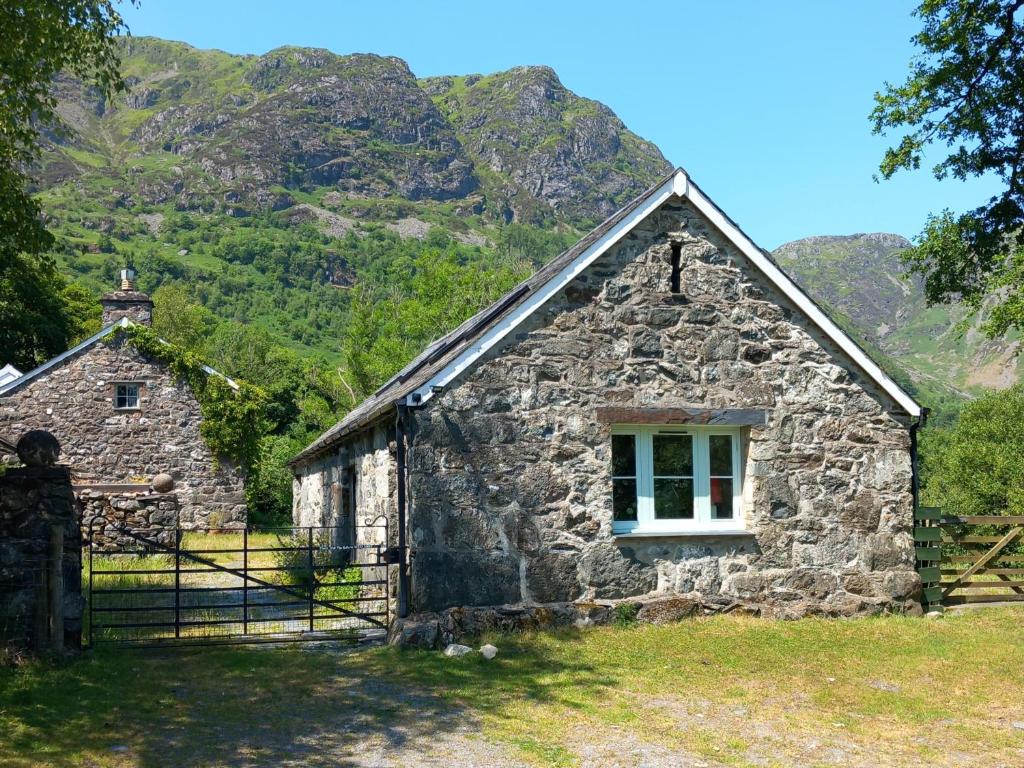 an old stone building with a window and mountains in the background at Gesail Barn and Farmhouse in Machynlleth