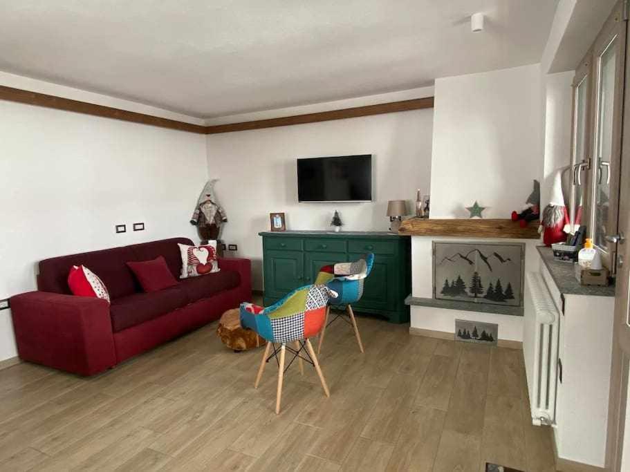 salon z czerwoną kanapą i kominkiem w obiekcie Appartamento Gnomo Livigno w Livigno