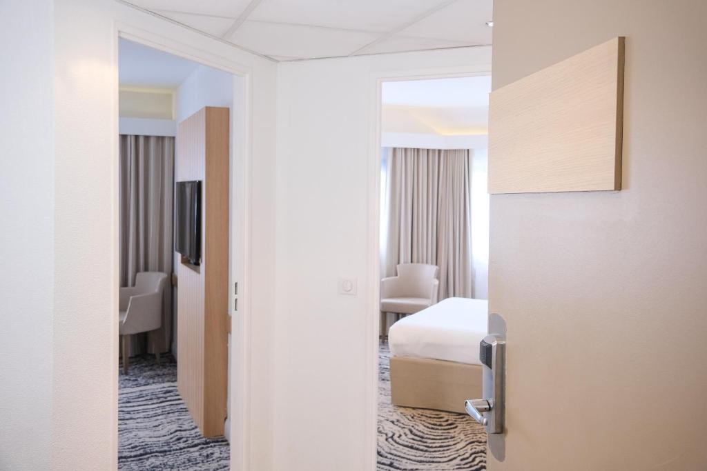 a room with a bed and a door to a bedroom at Thalazur Ouistreham - Hôtel & Spa in Ouistreham