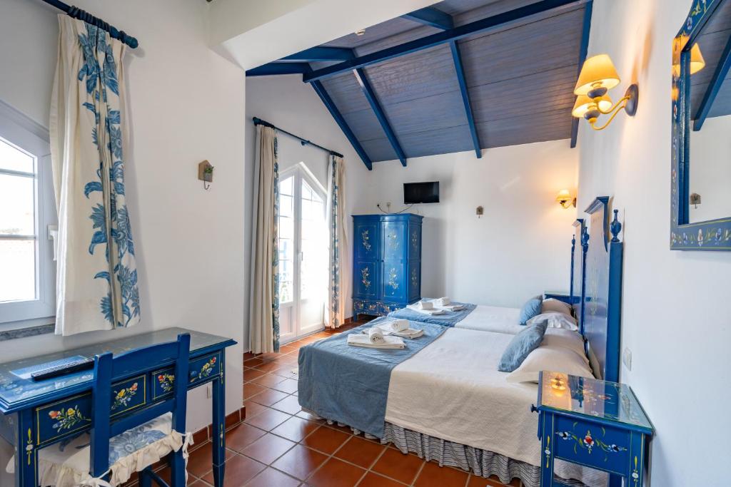 a bedroom with a bed and two blue tables at Hotel Mar e Sol VNMF by Umbral in Vila Nova de Milfontes