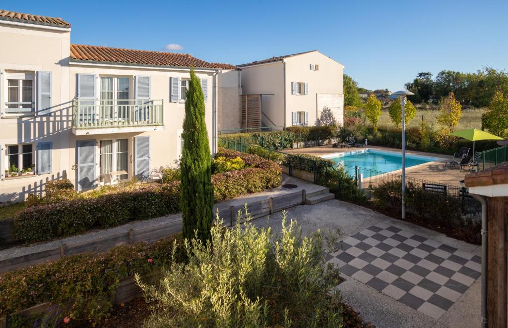 a view of a yard with a pool and houses at Résidence services Les Essentielles Sainte Soulle in Sainte-Soulle