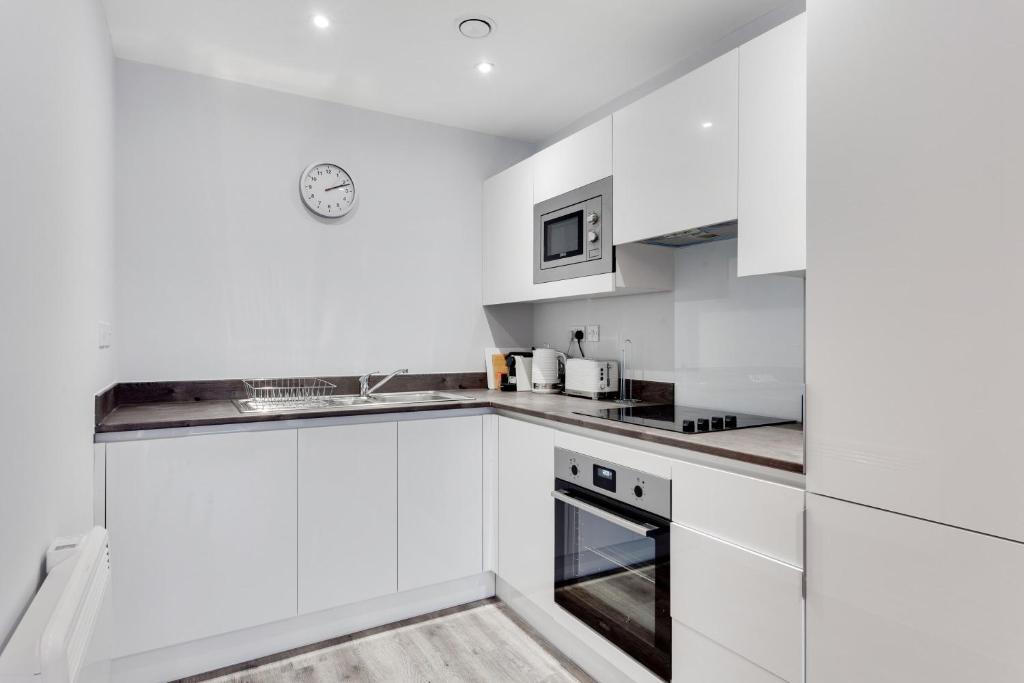 a white kitchen with white cabinets and appliances at Modern 1 Bedroom Flat In Central Birmingham in Birmingham