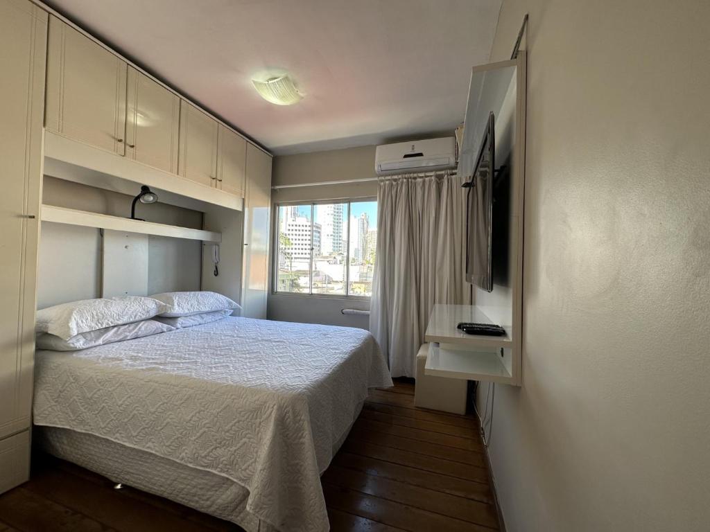 um pequeno quarto com uma cama e uma janela em Edificio Long Beach em Balneário Camboriú