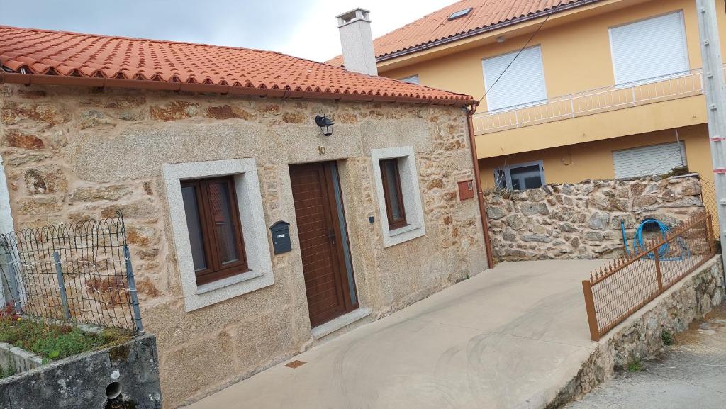 una casa de piedra con una pasarela junto a un edificio en Casa vacacional de pueblo en Ponte Do Porto