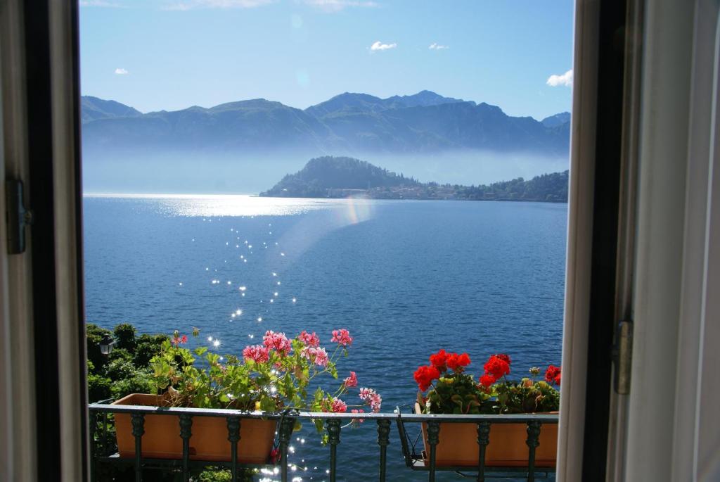 una ventana con flores y vistas al agua en Hotel Riviera, en Cadenabbia