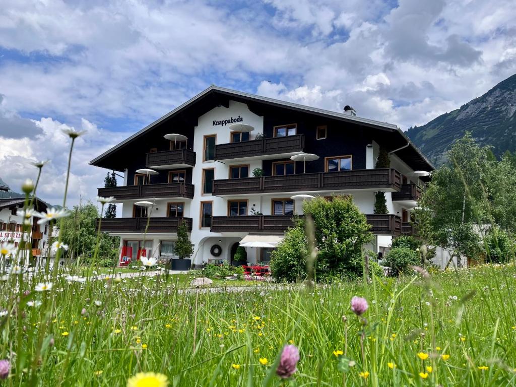 ein Gebäude mit einem Blumenfeld davor in der Unterkunft Appart Hotel Knappaboda in Lech am Arlberg