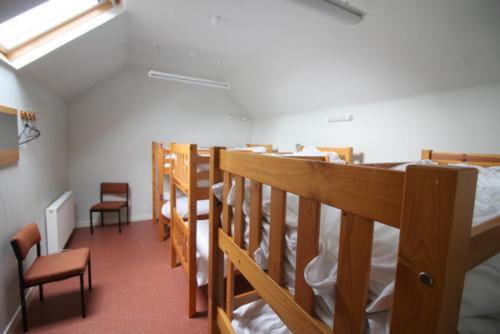 Pokój z szeregiem łóżek piętrowych i krzeseł w obiekcie Highlander Bunkhouse w mieście Huntly