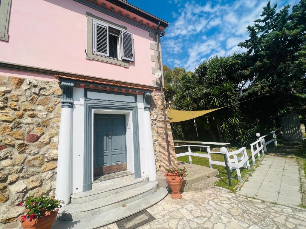 una casa rosa con una puerta azul y una valla blanca en Be Your Home - Villa Rosi, en Civitavecchia