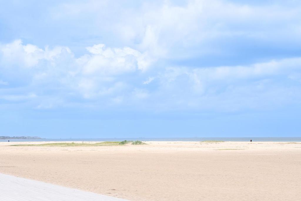 a sandy beach with a blue sky and clouds at Thalazur Ouistreham - Hôtel & Spa in Ouistreham