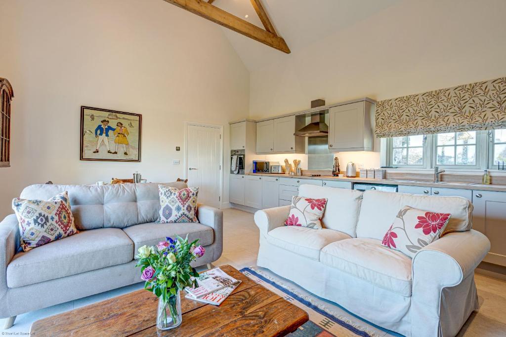 a living room with two couches and a kitchen at Dairy Lodge in Bladon