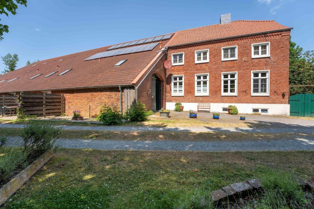 ein großes Backsteingebäude mit Sonnenkollektoren darauf in der Unterkunft Grashaus Upleward in Krummhörn