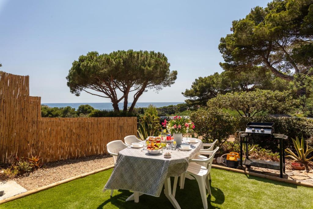 a table and chairs in a backyard with a fence at Le Photinia, mobil-home climatisé avec vue mer situé au cœur du domaine in Hyères