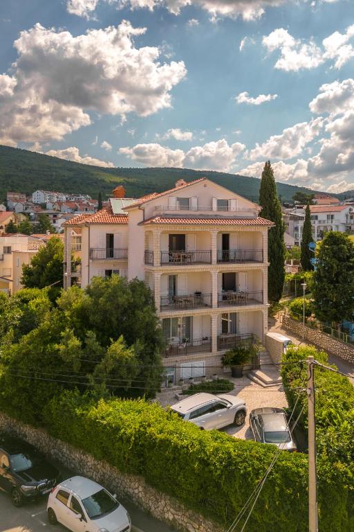 a building with cars parked in a parking lot at Apartments Lonzor in Selce