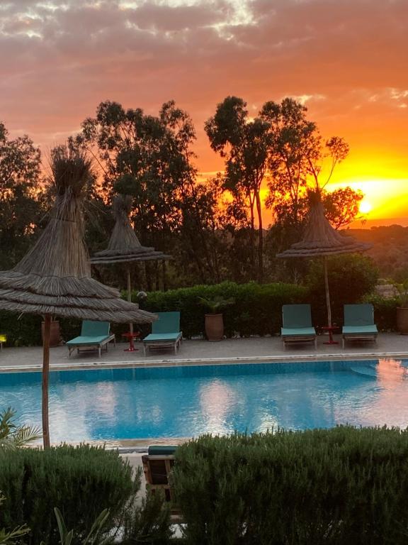 een zwembad met stoelen en parasols bij zonsondergang bij La Villa Sauvage in Essaouira