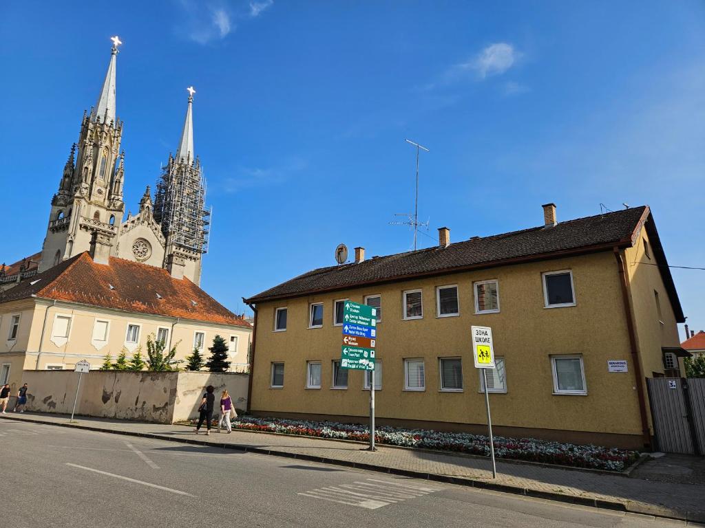 een gebouw op een straat met een kerk op de achtergrond bij Gerardus Apartmani 2 in Vršac