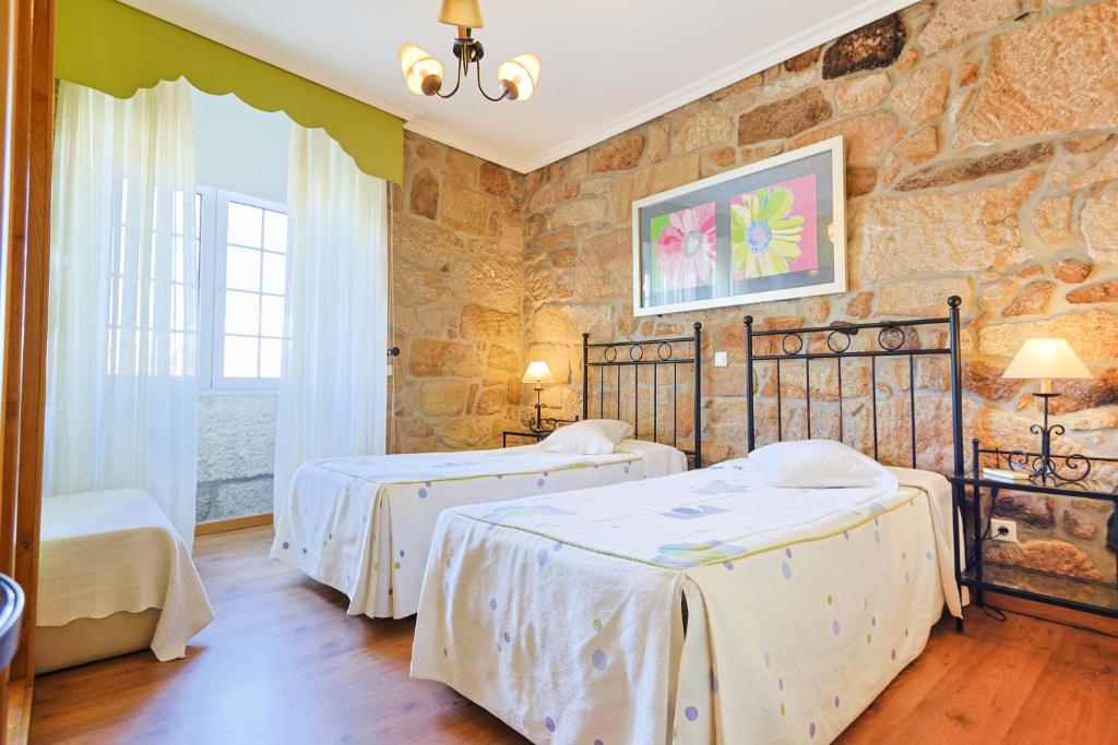 1 dormitorio con 2 camas y pared de piedra en Residencial Bem Estar, en Chaves