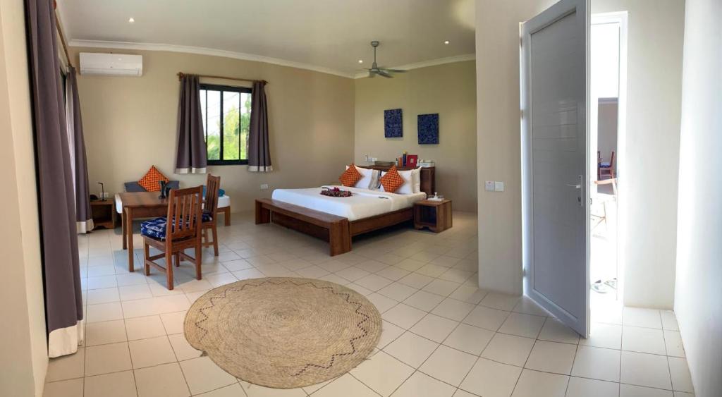 a bedroom with a bed and a dining room with a table at Coral House near Villa Bluu in Jambiani