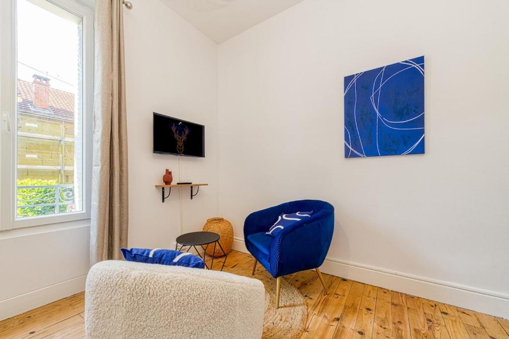 a living room with a blue chair and a window at 2 pièces tout confort, déco moderne, wifi fibre in Grenoble